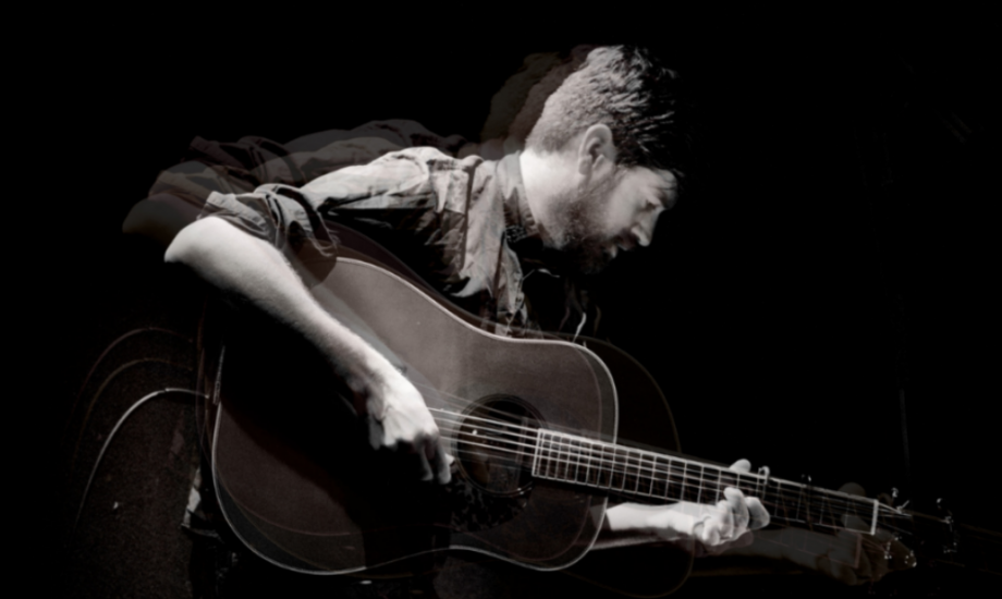 Kris Drever performs on stage in a monochrome image