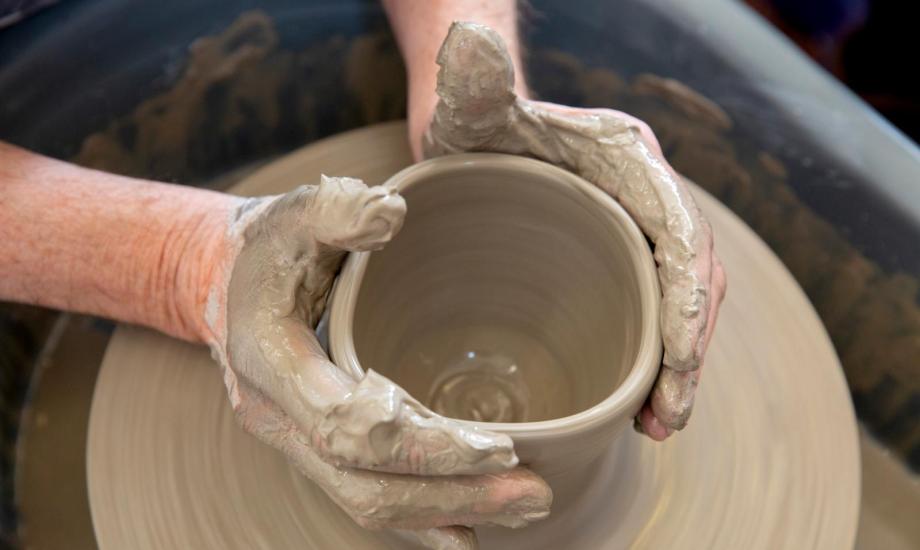 Close up of someone molding clay on a potters wheel