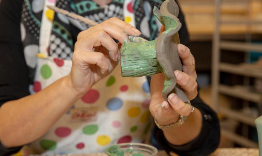 A close up image of someone painting pottery green
