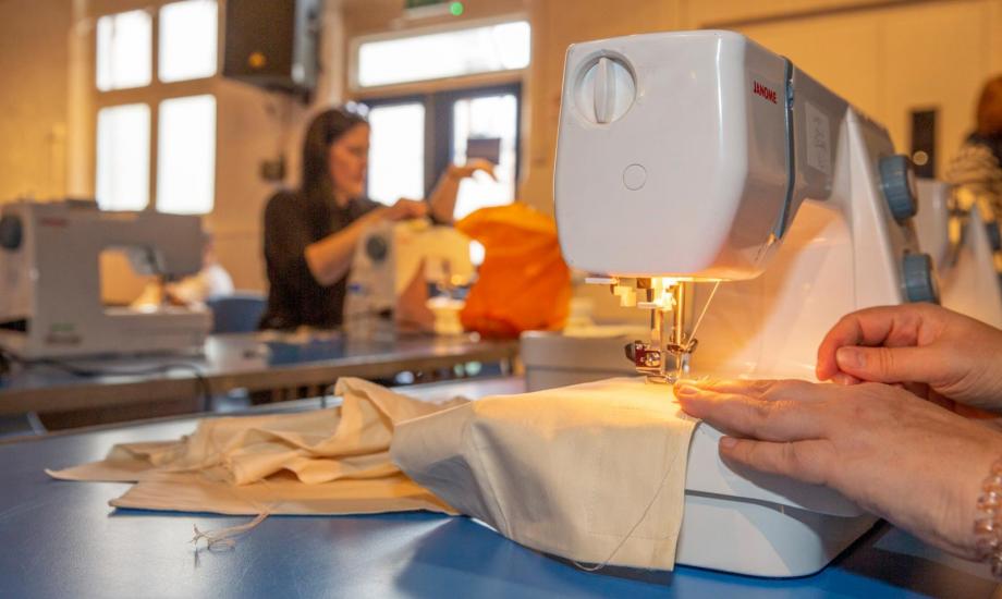 Image of a sewing machine being used to sew some cream cloth 